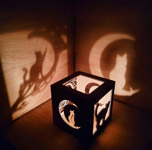 Light box with cat silhouette cutouts making cat shaped shadows 